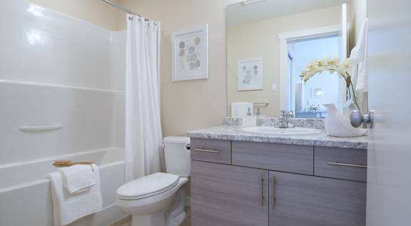 A white toilet sits next to a white bathtub in a bathroom.