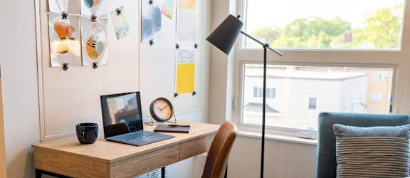 a desk with a laptop and a chair in a room with a window
