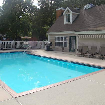 A small residential pool with a deck and a house in the background.