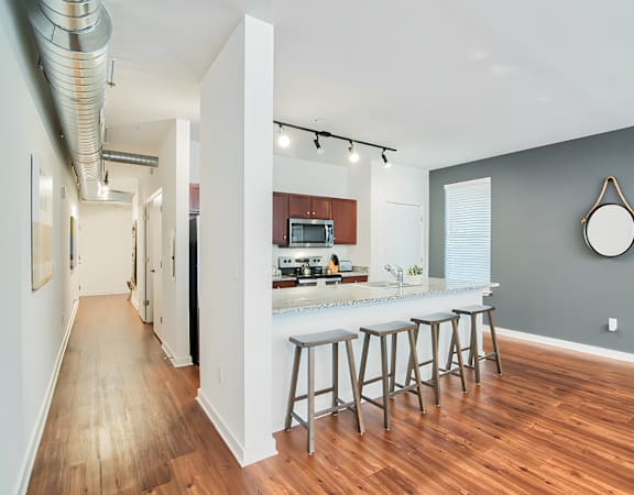an open kitchen with a bar and stools in a living room with a hallway