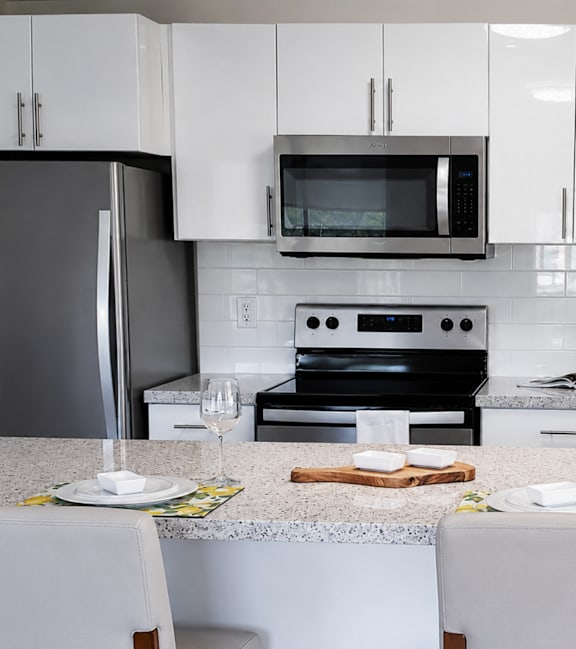 A modern kitchen with a stainless steel refrigerator and wooden flooring.