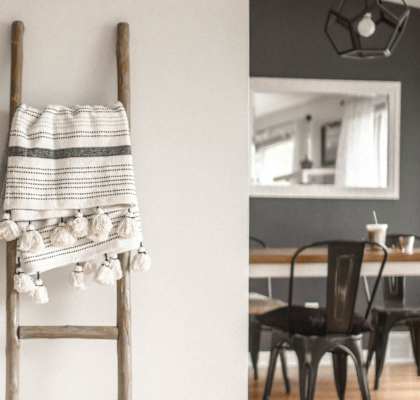 A striped towel is hanging on a wooden ladder in a room.