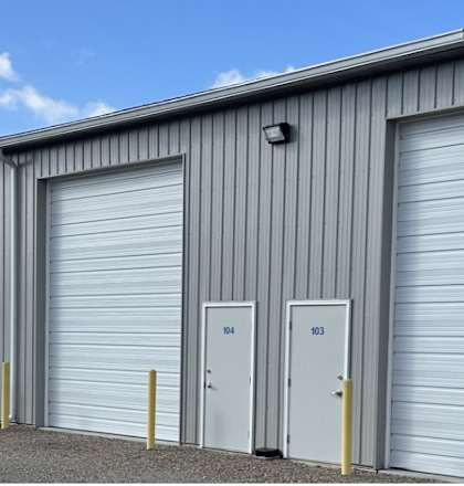A long row of storage units with white doors and grey walls.