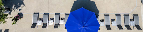 an overhead view of an infinity pool with umbrellas and chairs