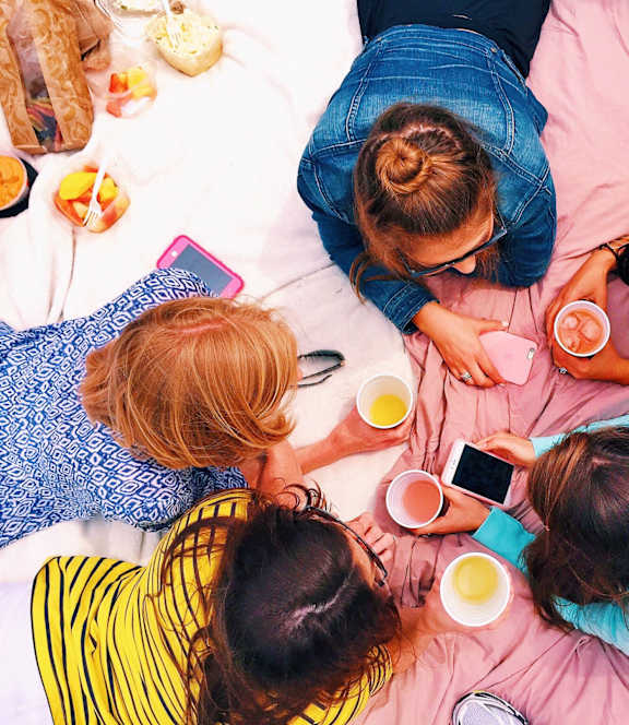 Four people are lying on a pink blanket with drinks and a cell phone. at Stratford at Southern Towers, Alexandria