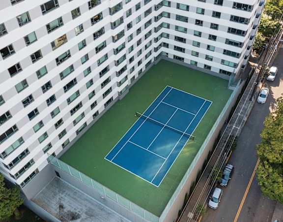an aerial view of a tennis court in front of a building