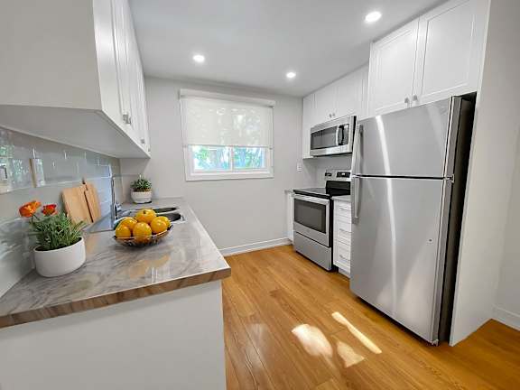 A kitchen with a refrigerator, oven, and sink.