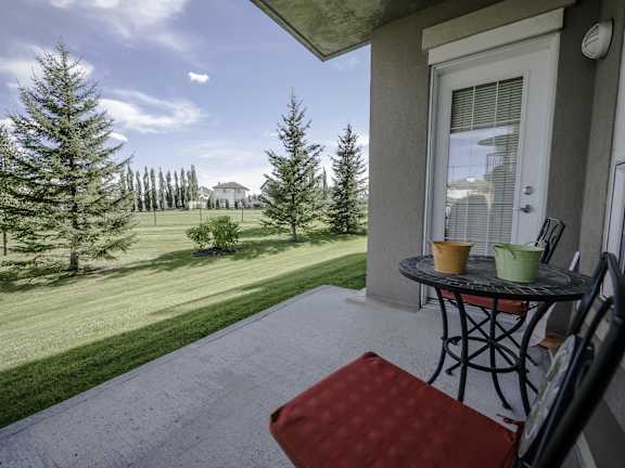 a patio with a table and chairs and a view of a golf course