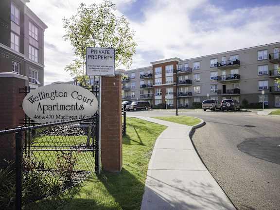 an apartment building on the side of a street with a sign in front of it