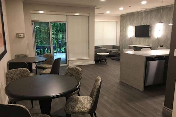 a room with tables and chairs and a kitchen and a tv