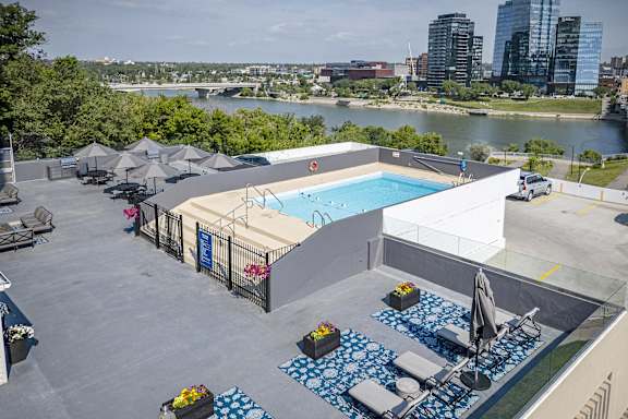 an aerial view of a pool and patio with chairs and umbrellas on top