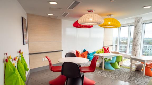 A room with a white table and colorful chairs.