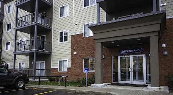 A parking lot in front of a building with a blue sign that says "Sunset Plaza Ave.".