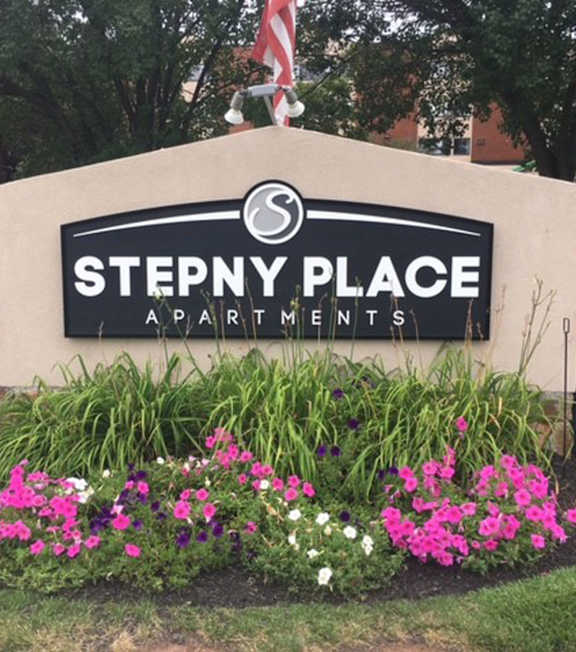 a stone retaining wall with a sign in front of a building  at Stepny Place, Connecticut, 06067