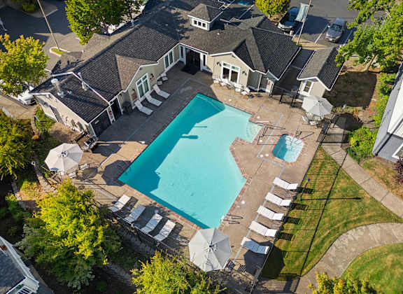 an aerial view of a swimming pool and patio with umbrellas and a house