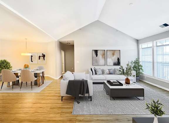 A modern living room with a grey sofa and a wooden dining table.