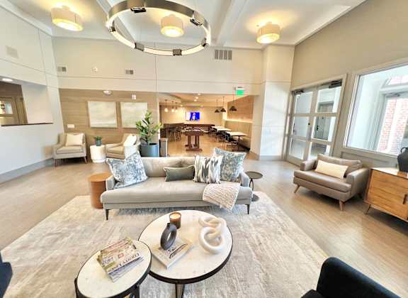 A spacious living room with a large grey sofa and a coffee table in the center.
