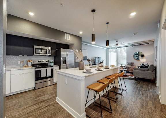 an open kitchen and living room with an island and bar stools at Linc, Iowa