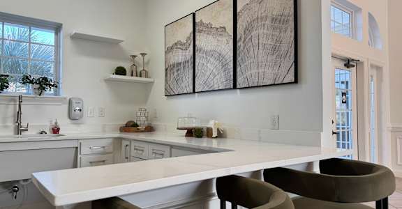 A modern kitchen with a large island and two chairs.