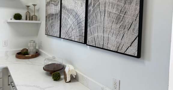 A large black and white artwork on a wall above a table.