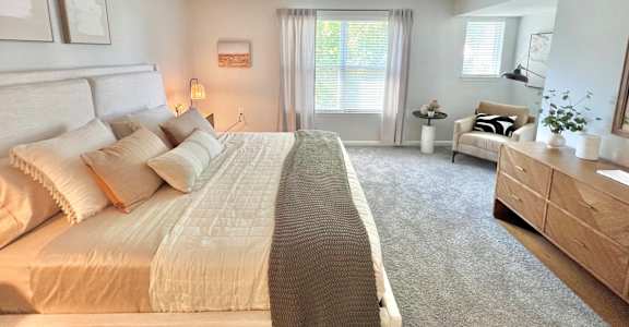 A bedroom with a large bed, a chair, and a dresser.