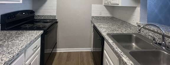 a kitchen with granite counter tops and white cabinets at Whispering Oaks in  Conroe, TX