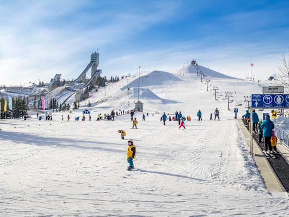 A group of people are skiing and snowboarding on a sunny day.