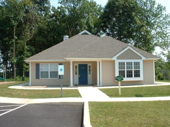 a small house in a parking lot with trees
