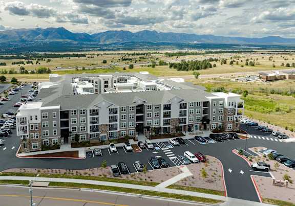 A large apartment complex with a parking lot in front.