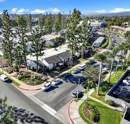 A sunny day in a suburban area with a parking lot and trees at THE STREAMS Apartments, Fullerton, 92831