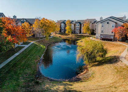 an aerial view of a pond with houses in the background at 92West, West Des Moines