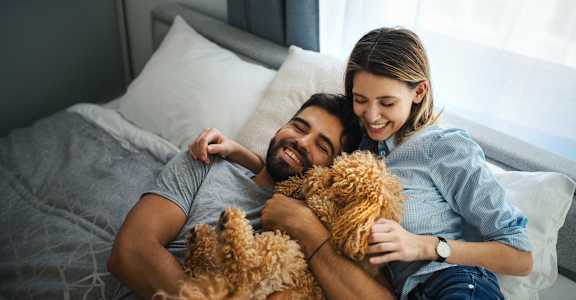 a man and woman laying on a bed with two dogs