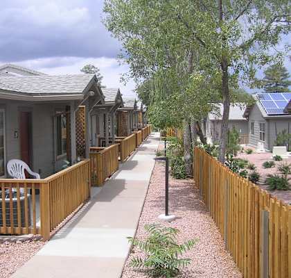 A row of houses with wooden fences and a sidewalk.