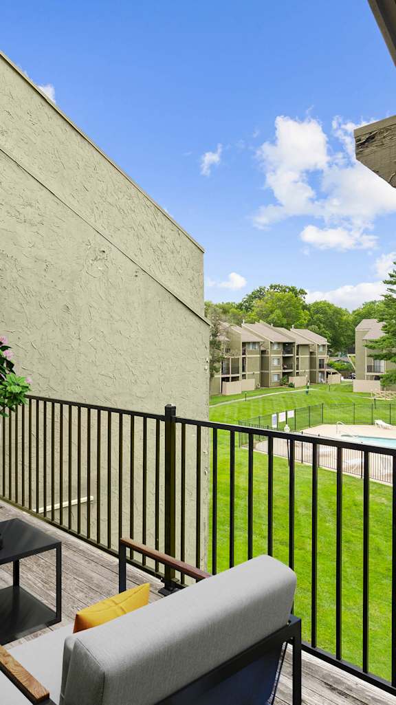 A balcony with a table and chairs overlooking a pool.