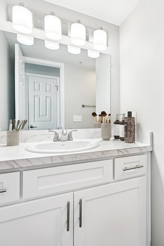 A white bathroom with a sink, mirror, and toilet.