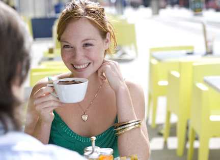 A woman in a green dress is enjoying a cup of coffee.