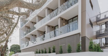 an apartment building with balconies and a tree in front of it