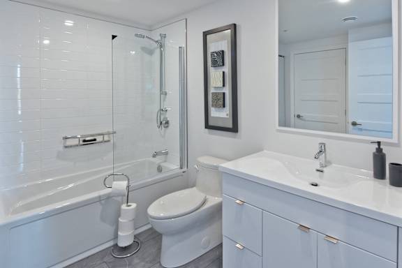 A white bathroom with a toilet, sink, and shower.