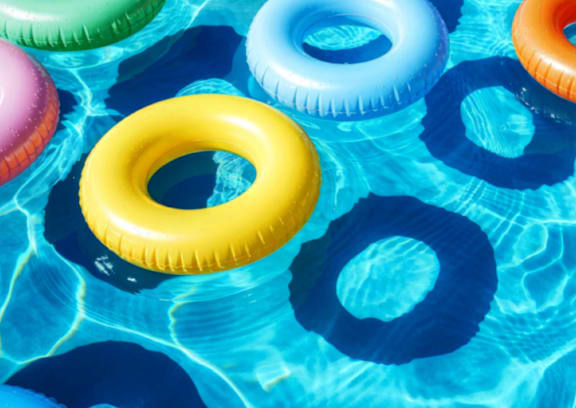 A group of colorful inflatable rings floating in a pool.