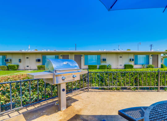 Enclosed Picnic Area Featuring Grill and Covered Tables with Bench Seating, Surrounded by Lush Landscaping and Las Brisas Apartment Buildings at Las Brisas Apartments, Colton