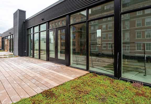 A modern building with a glass facade and a brick walkway in front.