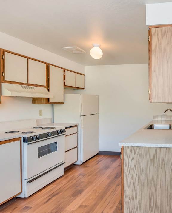 A kitchen with white appliances and wooden cabinets.