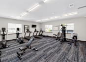 Thumbnail 9 of 11 - A gym with a variety of equipment including treadmills, weights, and exercise machines.