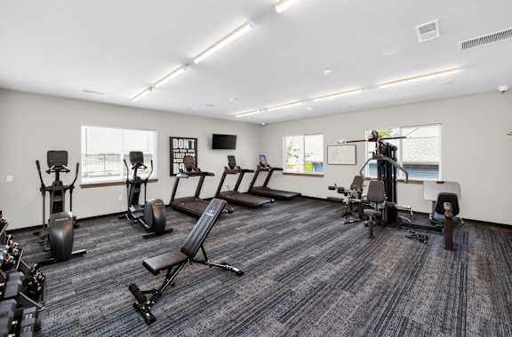 A gym with a variety of equipment including treadmills, weights, and exercise machines.
