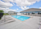 Thumbnail 5 of 11 - A swimming pool surrounded by a concrete patio and metal railings.