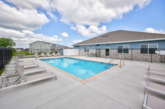 A swimming pool surrounded by a concrete patio and metal railings.