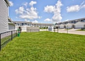 Thumbnail 11 of 11 - A grassy area in front of a row of houses with a fence and a green trash can.