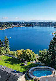 A large body of water surrounded by trees and a house with a pool.