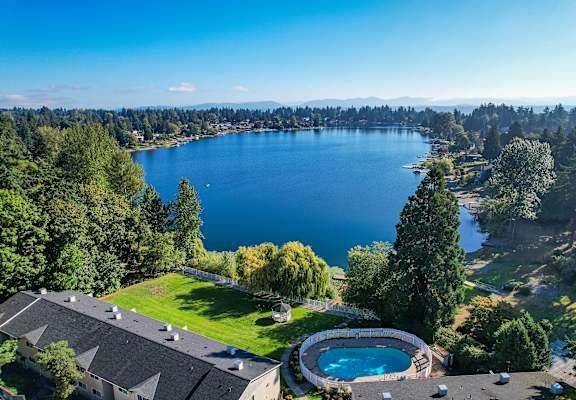 A large body of water surrounded by trees and a house with a pool.