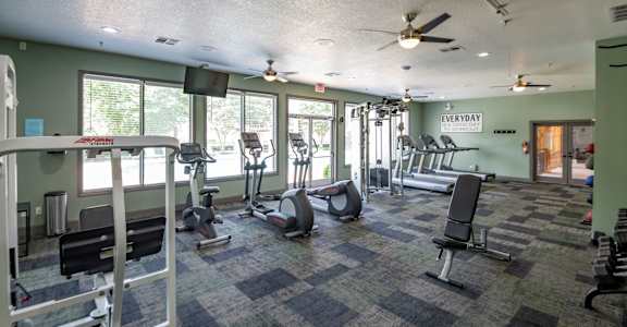 A gym with a variety of equipment including treadmills, weights, and exercise machines.